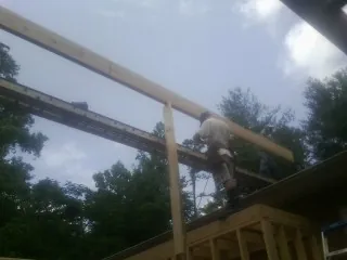 Carpenter setting a ridge beam over a new addition frame — Ice Dam Removal by Roofing Brothers in Baldwinsville