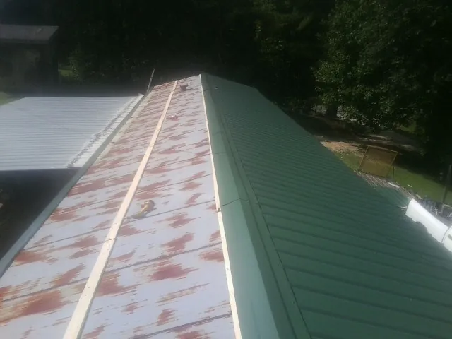 Old rusted panels beside newly installed green metal roofing — Wind Damage Roof Repair by Roofing Brothers in Baldwinsville