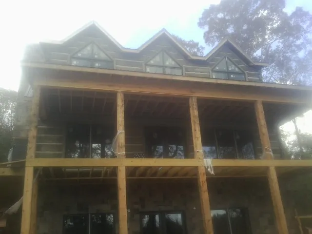 Dormers and porch framing on a large log home under construction — Roof Coating work by our crew in Baldwinsville
