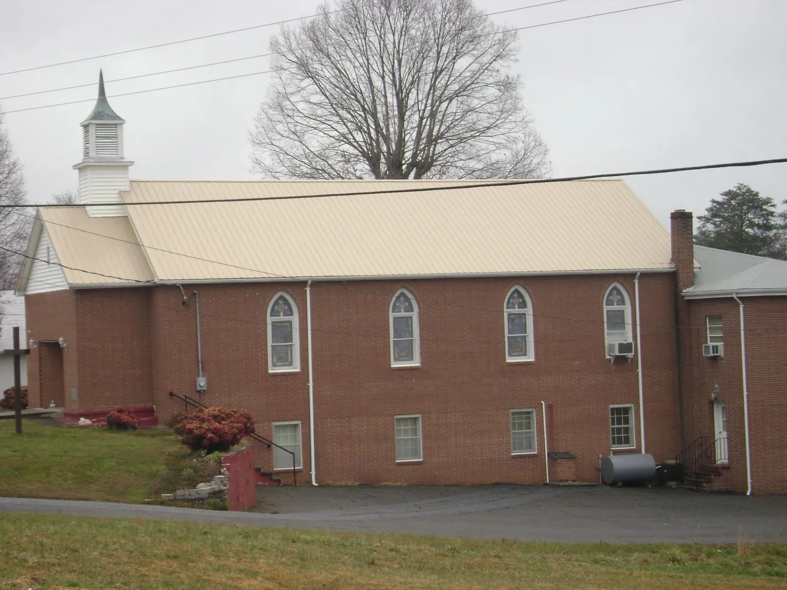 New tan metal roof on a brick church with a white steeple in Baldwinsville