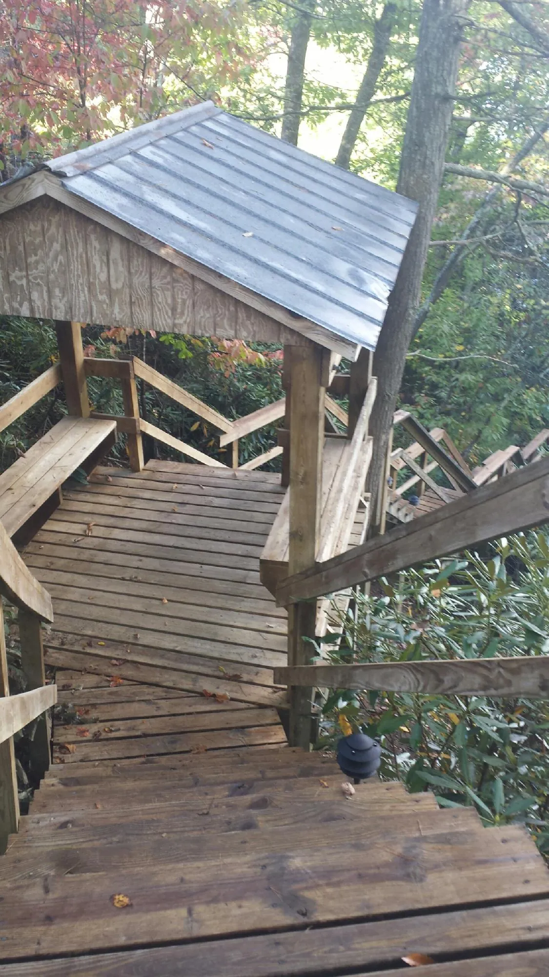 Metal roofed shelter over wooden steps on a wooded walkway — Skylight Repair & Installation work by our crew in Baldwinsville