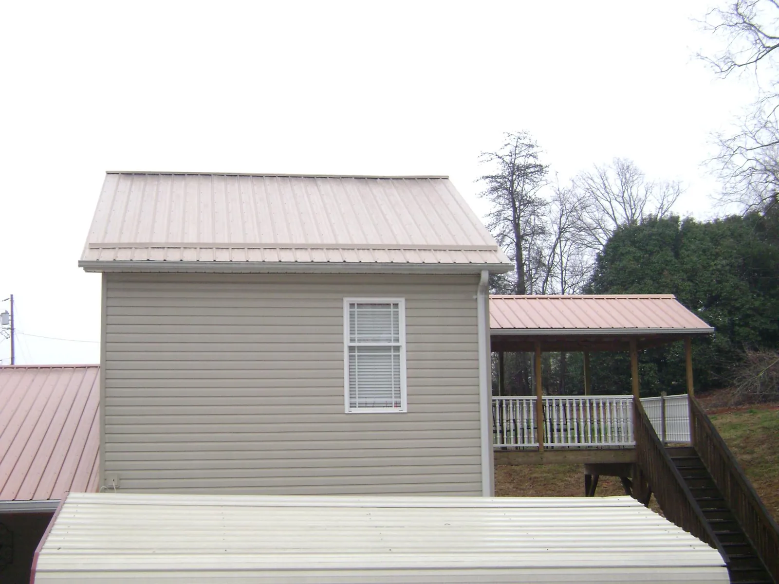 Tan metal roofs on a two story addition and attached porch, from a Roof Replacement job in Baldwinsville