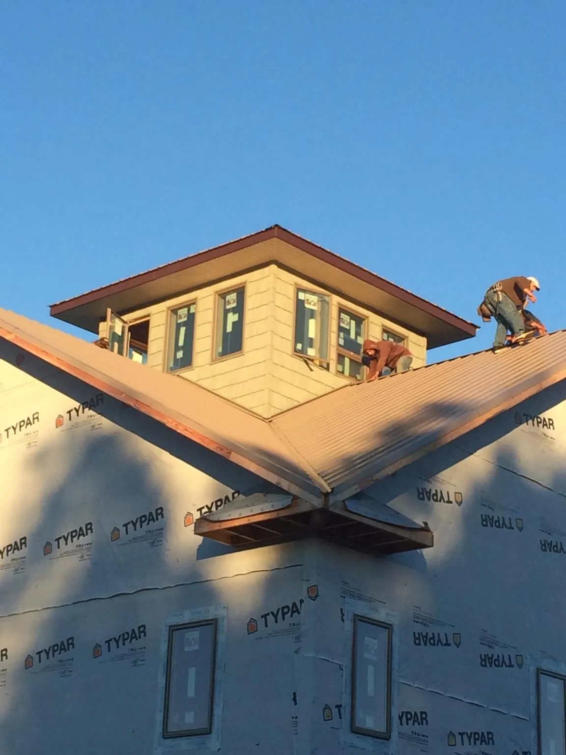 Roofers working around a rooftop cupola on a new metal roof at sunset — Roof Waterproofing in Baldwinsville by Roofing Brothers